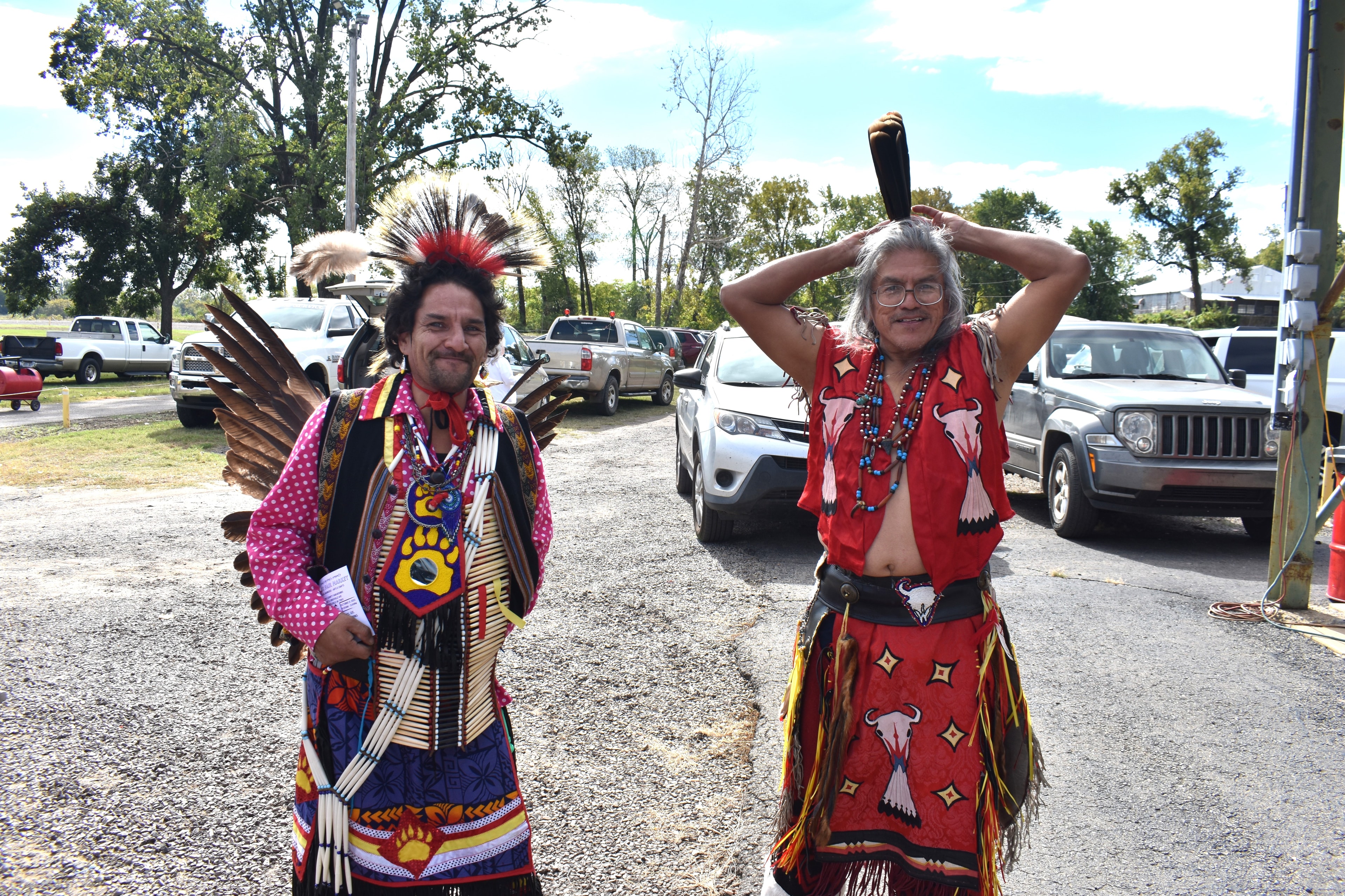 Two Cherokee dancers smiling in full traditional regalia between performances