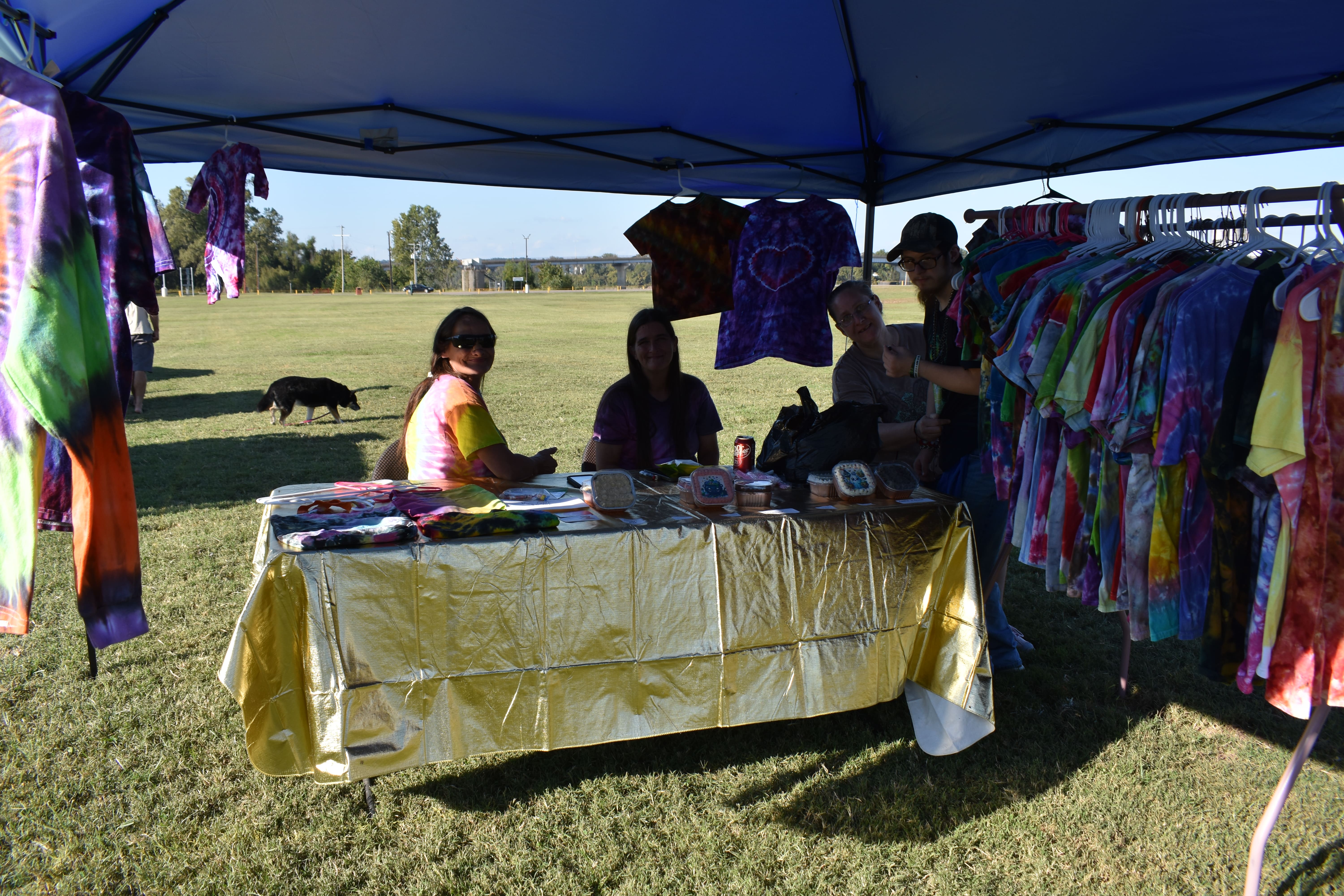 Tie-dye shirt vendor booth with four people smiling at October Festival 2025