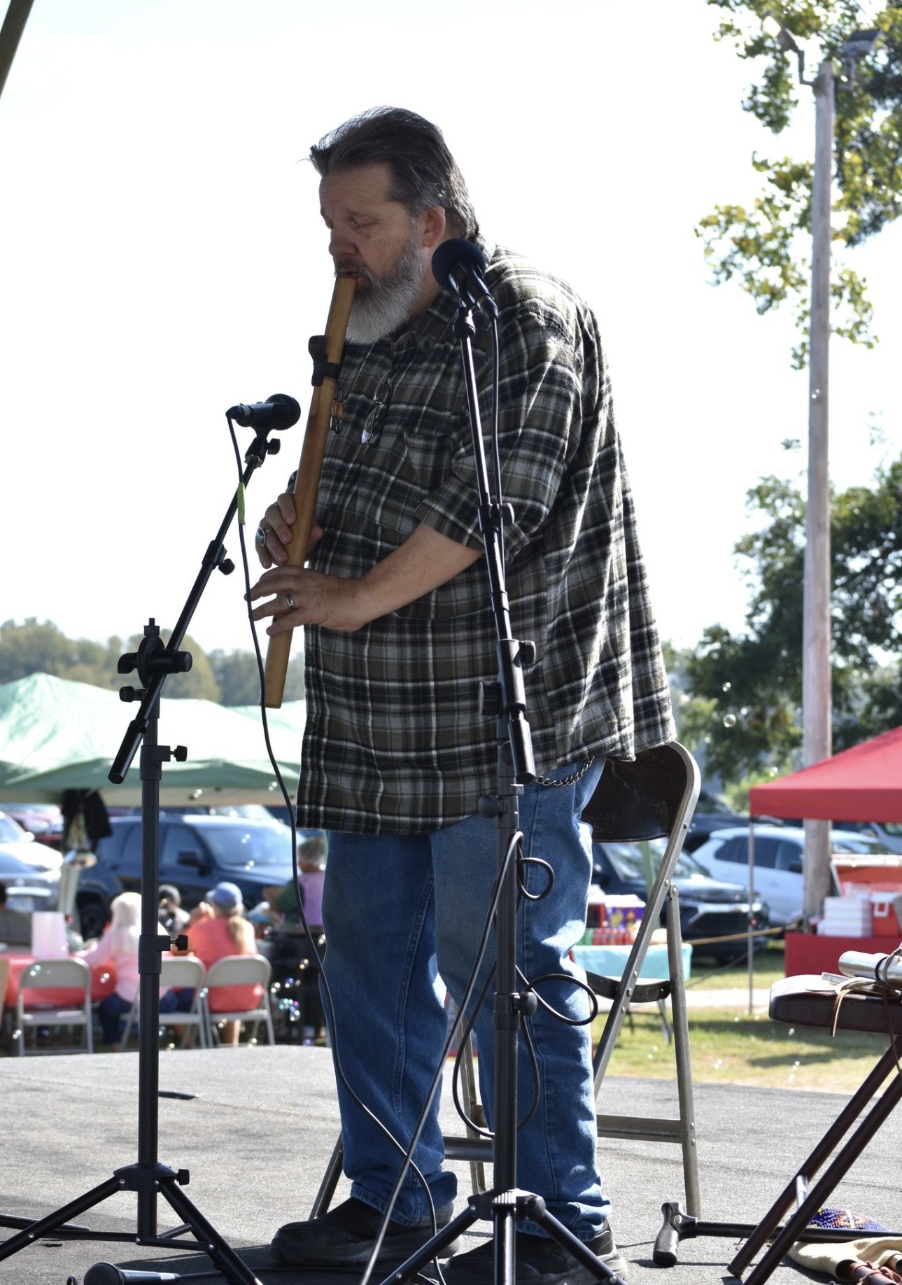 Cherokee flute player performing on stage at outdoor gathering