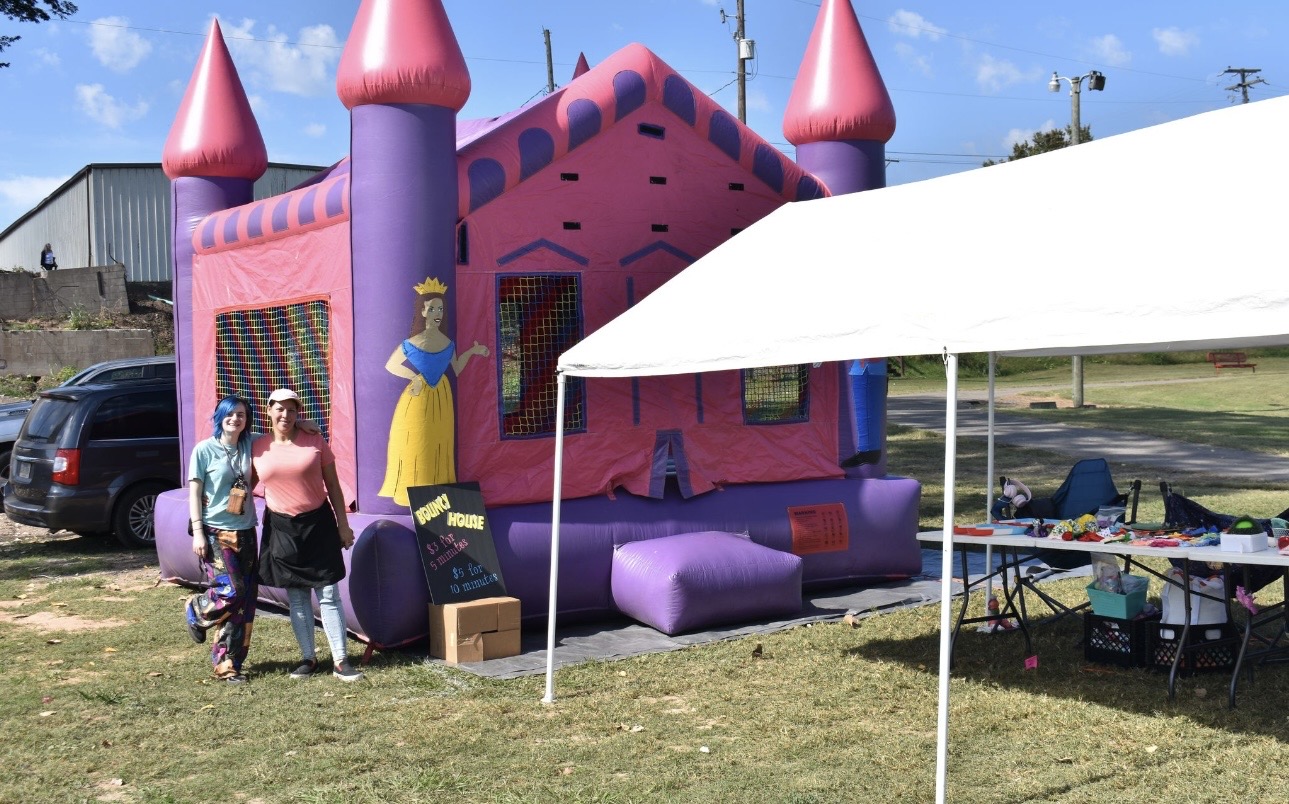 Two women standing in front of bounce house at Cherokee Chickamauga event