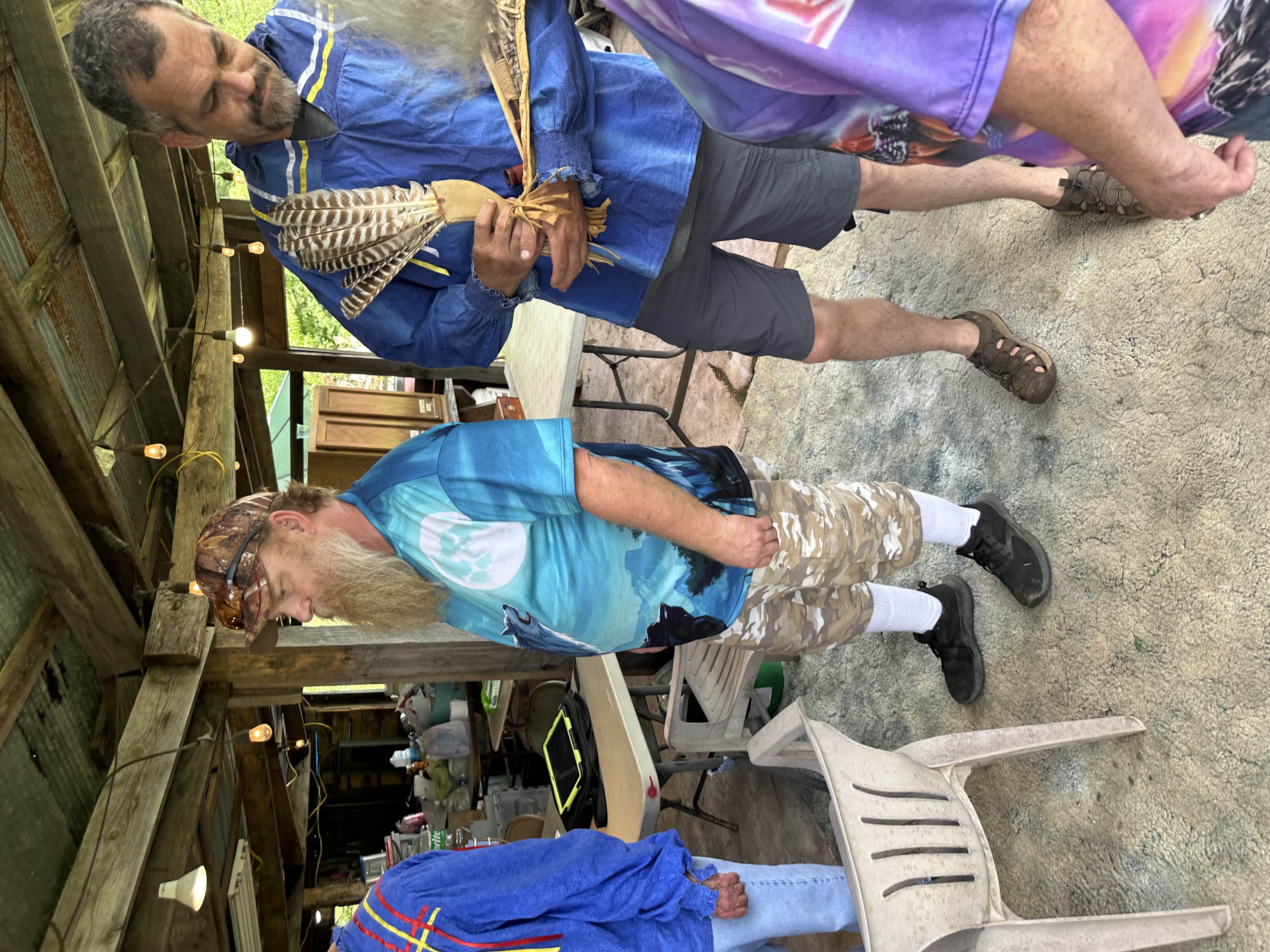 Tribal member in ribbon shirt holding sacred turkey feathers and ceremonial pipe at Green Corn Ceremony 2026